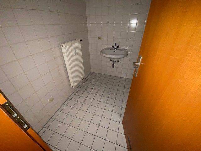 Kleiner, einfach gefliester Raum mit Waschbecken und Heizkörper, möglicherweise ein Gäste-WC.