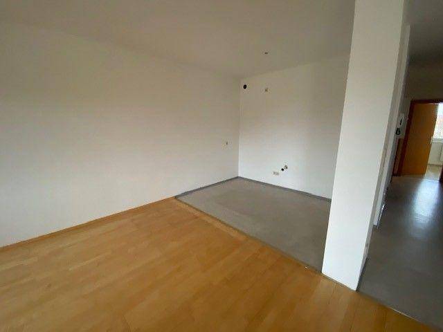 Heller Wohnbereich mit Parkettboden, der in einen gefliesten Bereich übergeht, ideal für eine offene Gestaltung.