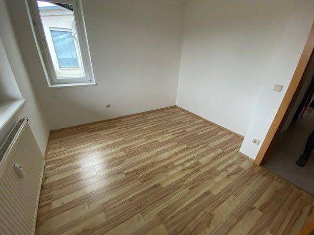 Gemütliches Schlafzimmer mit Laminatboden und einem Fenster, das eine ruhige Atmosphäre schafft.