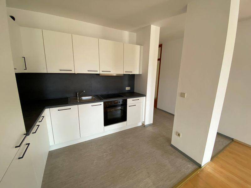 Funktionale, moderne Küche mit weißen Schränken und dunkler Arbeitsplatte, offen zum Wohnbereich.