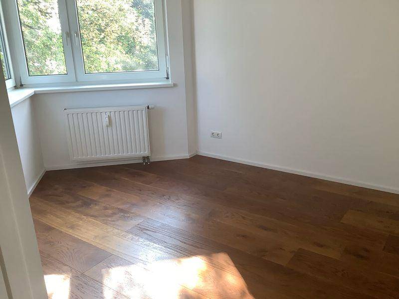 Lichtdurchfluteter Raum mit Holzboden und großem Fenster, ideal für ein Schlaf- oder Arbeitszimmer.