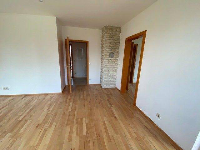 Geräumiger Wohnbereich mit hellem Laminatboden und einem dekorativen Steinsäulen-Element.