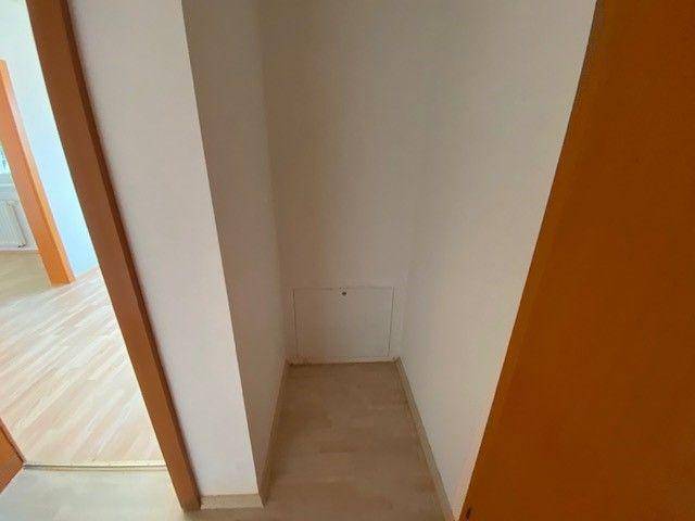 Kleiner Abstellraum oder Nische mit hellem Laminatboden und weiß gestrichenen Wänden.