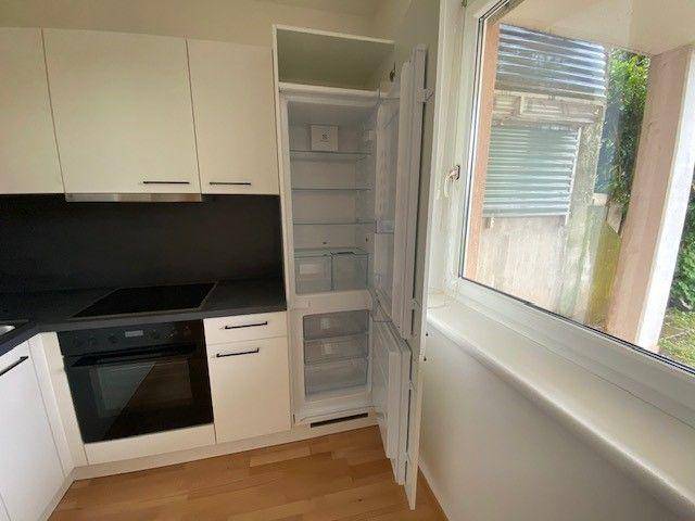 Integrierter Kühlschrank in der Küche mit geöffneter Tür und weiteren Einbaugeräten.