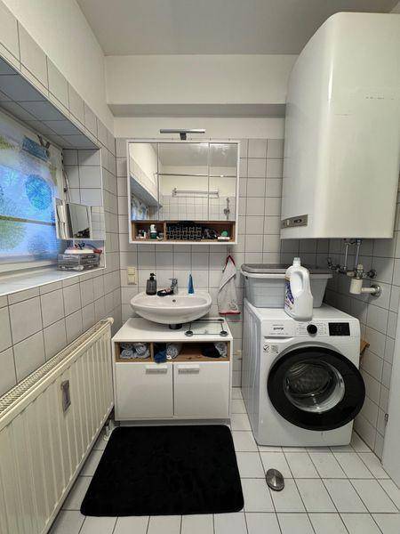 Funktionales Badezimmer mit Waschbecken, Spiegelschrank, Waschmaschine und Boiler.