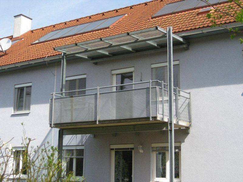 Detailansicht eines Balkons mit Metallgeländer und Überdachung am Gebäude.