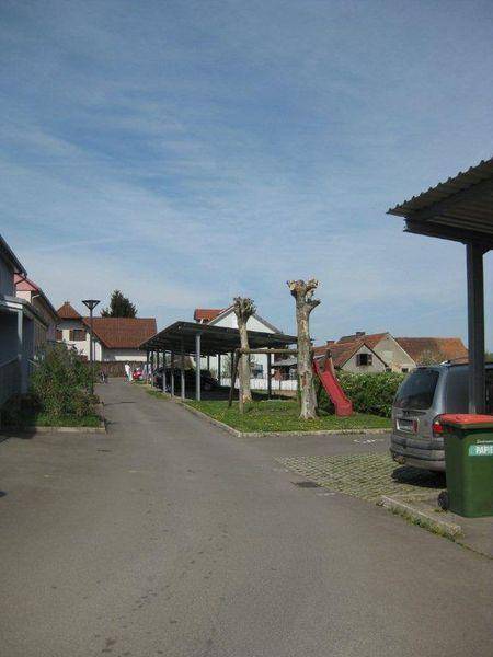 Wohngegend mit Carports, Spielplatz und weiteren Häusern im Hintergrund.