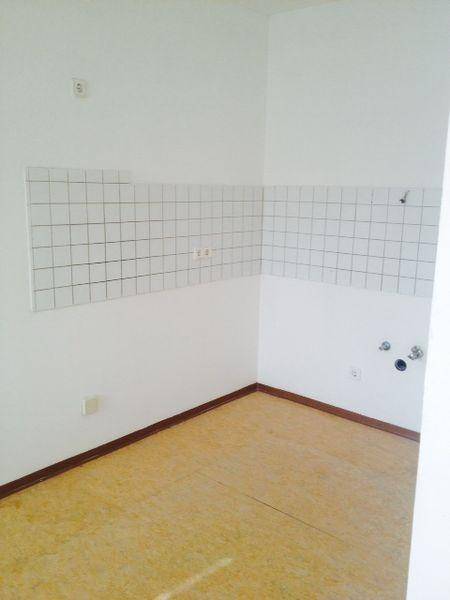 Leerer Küchenbereich mit gefliestem Fliesenspiegel und Anschlüssen für Geräte.