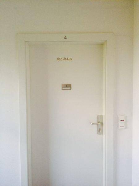 Nahaufnahme einer Wohnungstür mit Nummer und Klingelschild im Flur.