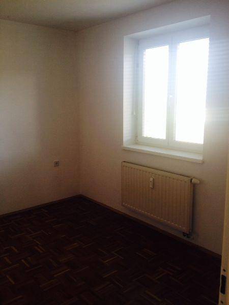 Helles Zimmer mit Parkettboden und Fenster, das viel Tageslicht hereinlässt.
