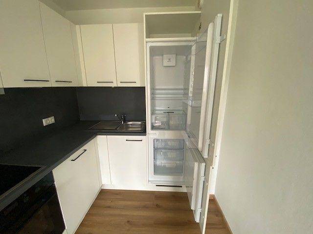 Moderne Küche mit integriertem Kühlschrank und weißen Schränken.