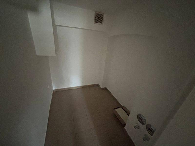 Kleiner Abstellraum oder Technikraum mit Fliesenboden und Lüftungsgitter an der Decke.