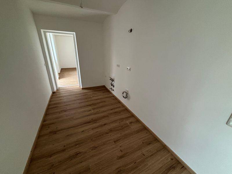 Raum mit Laminatboden und Anschlüssen für eine mögliche Küchenzeile oder Waschmaschine.