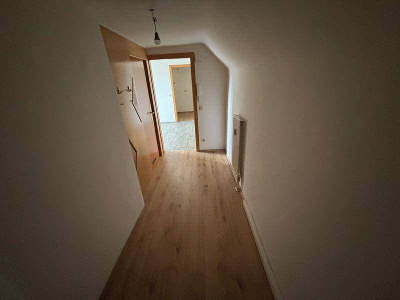 Schmaler Flur mit hellem Holzboden und offenen Türen, die weitere Räume zeigen.