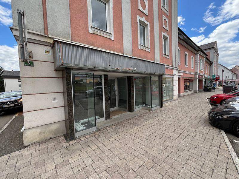Erdgeschossfassade eines Geschäftsgebäudes mit großen Schaufenstern und Zugang zur Straße.