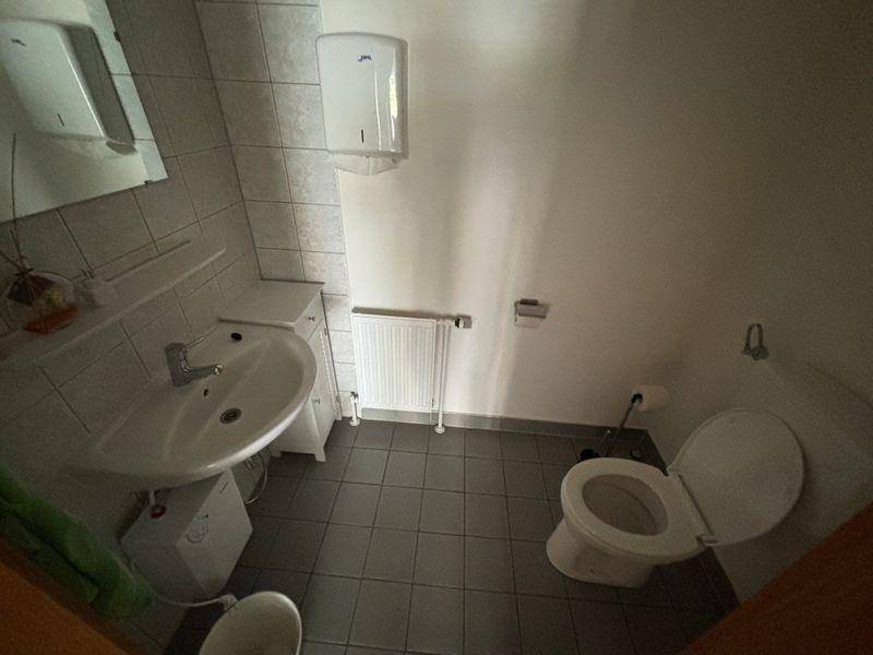Funktionale Gästetoilette mit Waschbecken, WC und Fliesenboden in neutralen Farben.