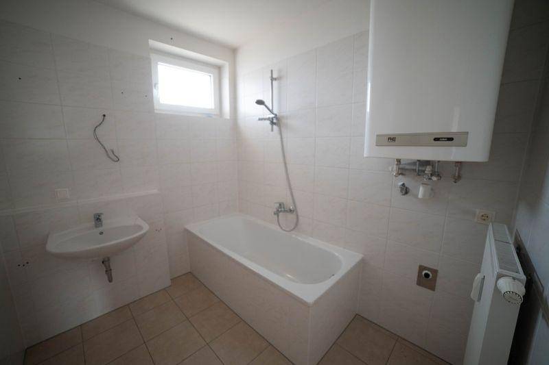 Funktionales Badezimmer mit Badewanne, Duschvorrichtung, Waschbecken und Fenster.