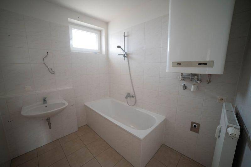 Funktionales Badezimmer mit Badewanne, Duschvorrichtung, Waschbecken und Fenster.