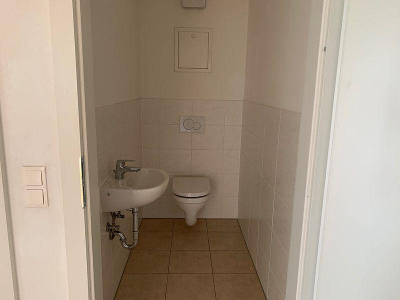 Kleines Gäste-WC mit Wand-WC, Waschbecken und hellen Fliesen, funktional und sauber.