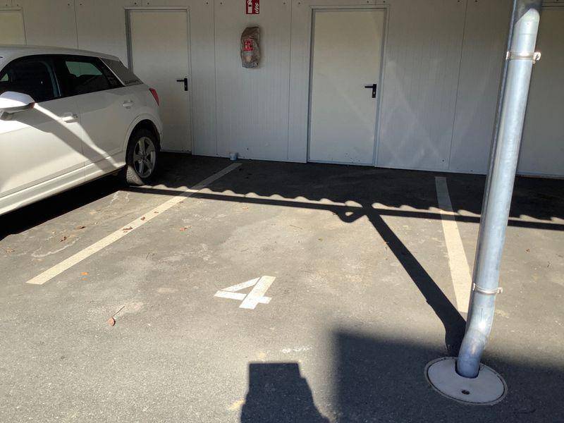 Überdachter Parkplatz mit Stellplatz Nummer vier und angrenzenden Abstellräumen.