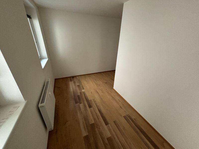 Helles Schlafzimmer mit Dachschräge, Holzfußboden und Fenster, bereit zur Einrichtung.