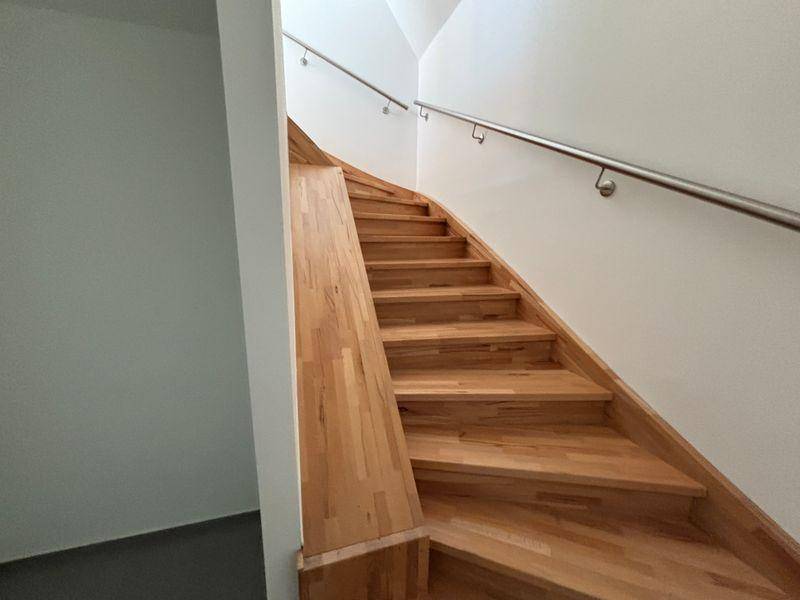 Moderne Holztreppe mit Edelstahlgeländer, die verschiedene Etagen des Hauses verbindet.