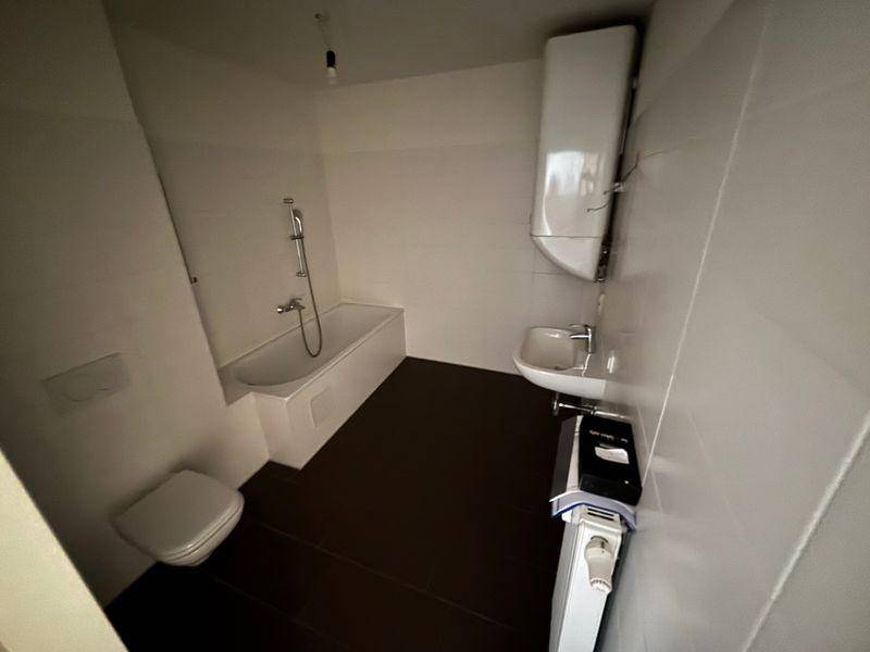 Modernes Badezimmer mit weißen Fliesen, Badewanne, Toilette und Waschbecken.