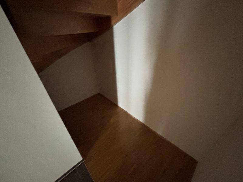 Kleiner Bereich unter der Holztreppe mit Parkettboden, ideal als Abstellfläche nutzbar.