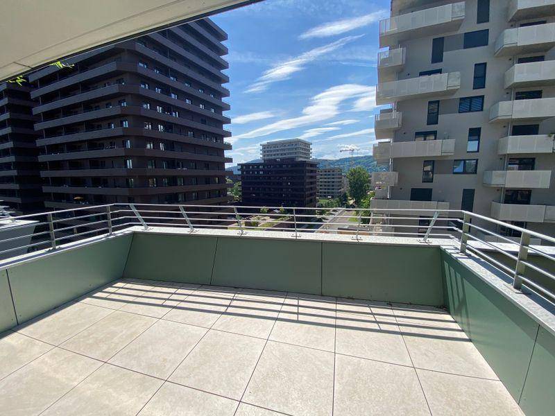 Weitläufige Terrasse mit Fliesenboden und modernem Geländer, umgeben von städtischer Architektur.