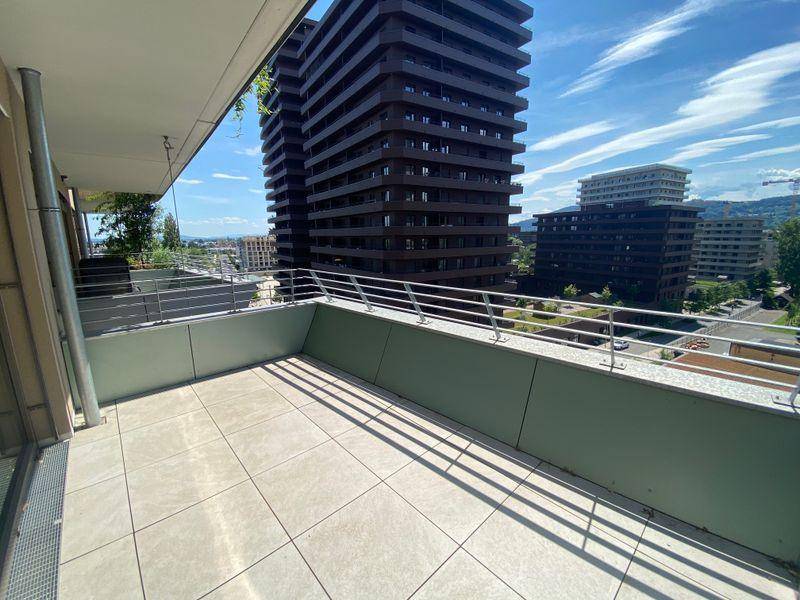 Lange, geflieste Terrasse mit Blick auf die städtische Umgebung und angrenzende Gebäude.