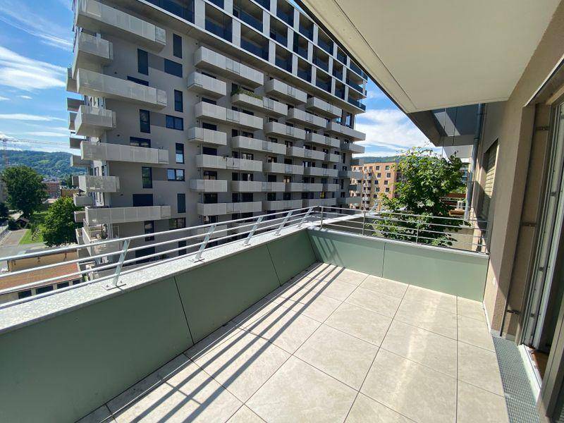 Eckterrasse mit Fliesenboden und modernem Geländer, bietet einen weiten Blick über die Stadt.