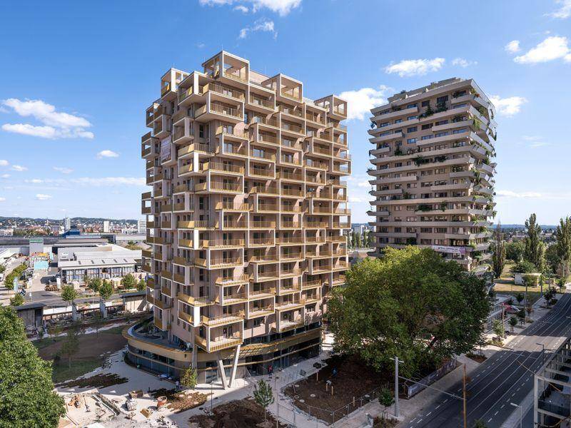 Luftaufnahme von zwei modernen Wohnhochhäusern mit vielen Balkonen in städtischer Umgebung.
