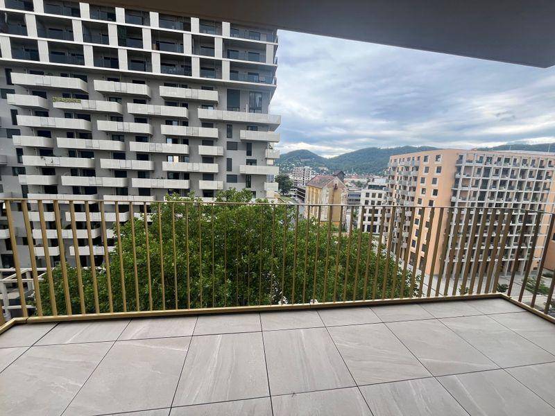 Geräumiger Balkon mit Fliesenboden und Blick auf die Stadt und die umliegenden Hügel.