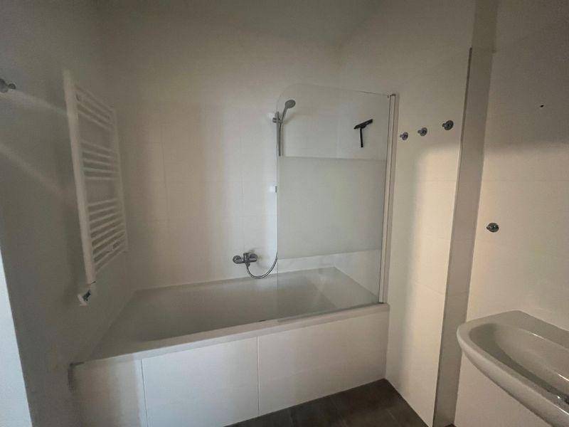 Modernes Badezimmer mit Badewanne, Duschabtrennung und beheiztem Handtuchhalter.