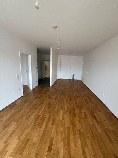 Geräumiger, heller Raum mit neuem Holzparkettboden und weißen Wänden, bereit zum Einzug.