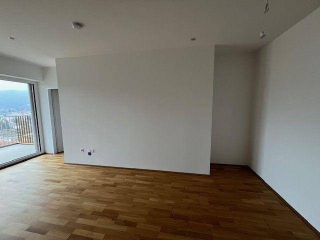 Heller Raum mit Parkettboden und Zugang zu einem Balkon, ideal für Wohn- oder Schlafbereich.
