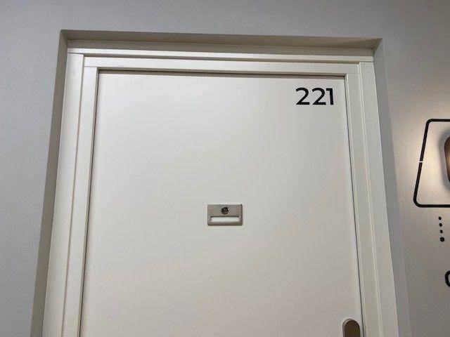 Weiße Wohnungstür mit der Nummer 221 in einem modernen Flur.