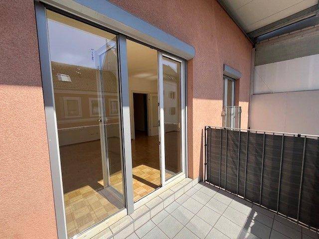 Balkon mit Fliesenboden und großer Schiebetür, die in den Innenbereich führt.