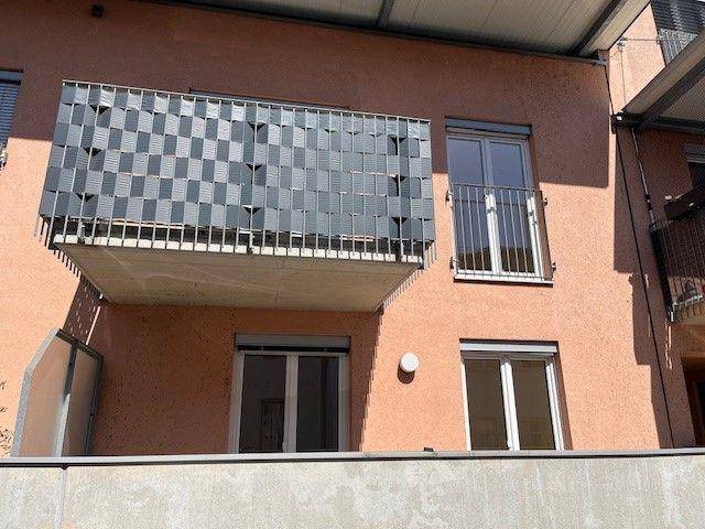 Balkon mit modernem Sichtschutz und Blick auf die Umgebung des Gebäudes.