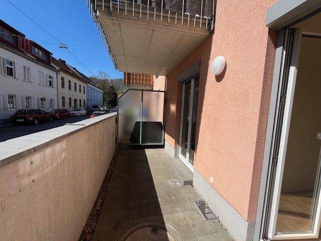 Schmaler Außenbereich mit Fliesenboden und Zugang zum Gebäude, ideal für Pflanzen.