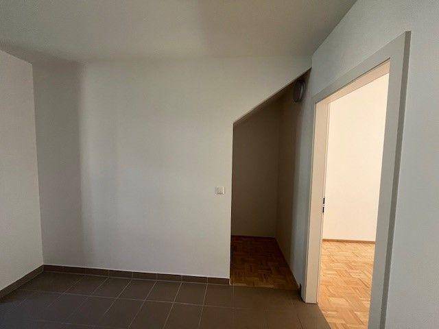 Raum mit Fliesenboden und einem praktischen Abstellbereich unter der Treppe.