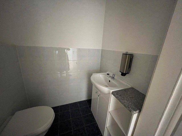 Kleines Gäste-WC mit Waschbecken, Toilette und dunklen Bodenfliesen.