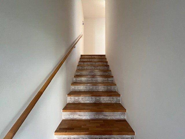 Holztreppe mit Geländer, die in das obere Stockwerk des Hauses führt.