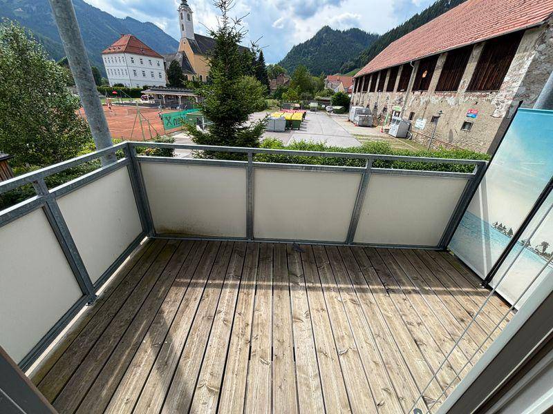 Balkon mit Holzboden und Blick auf die umliegende Berglandschaft und einen Tennisplatz.