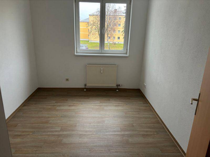 Geräumiges Zimmer mit Laminatboden und großem Fenster, ideal als Schlaf- oder Wohnbereich.