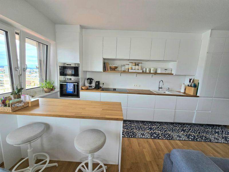 Helle, moderne Küche mit integrierten Geräten, Frühstücksbar und Stadtblick.