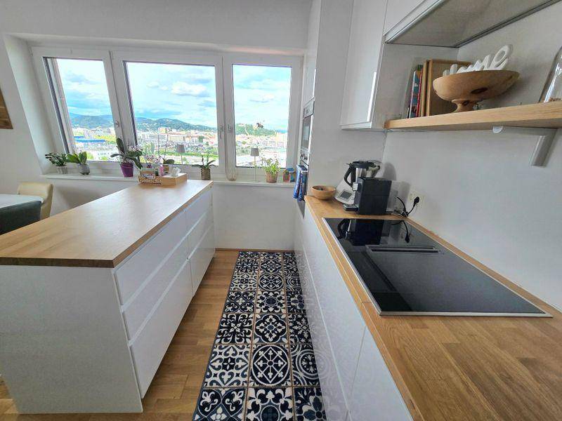 Detailansicht der modernen Küche mit Induktionskochfeld, Holzarbeitsplatte und Stadtblick.
