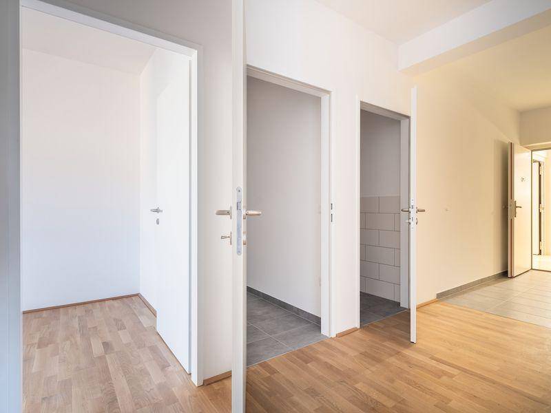 Heller Flur mit Holzfußboden und mehreren offenen Türen, die zu verschiedenen Räumen führen.