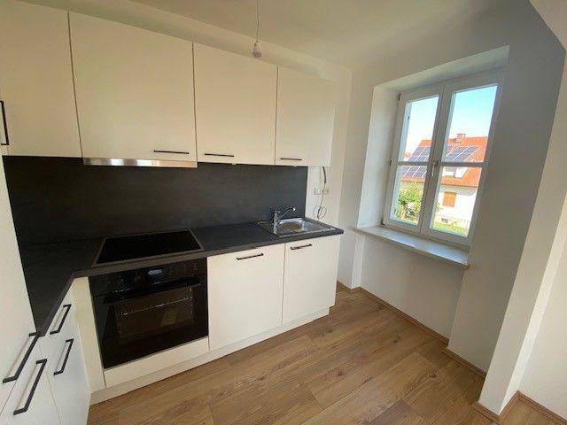 Helle Küche mit Fenster, das einen Blick auf die Nachbarschaft und Solaranlagen auf Dächern bietet.
