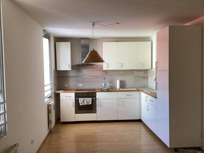 Moderne Einbauküche mit weißen Schränken, Holz-Arbeitsplatte und integriertem Backofen.